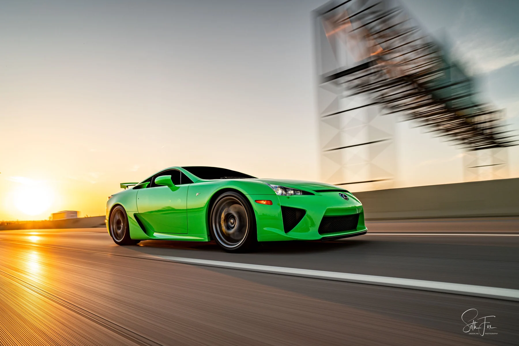 Green Lexus photographed in motion at sunset